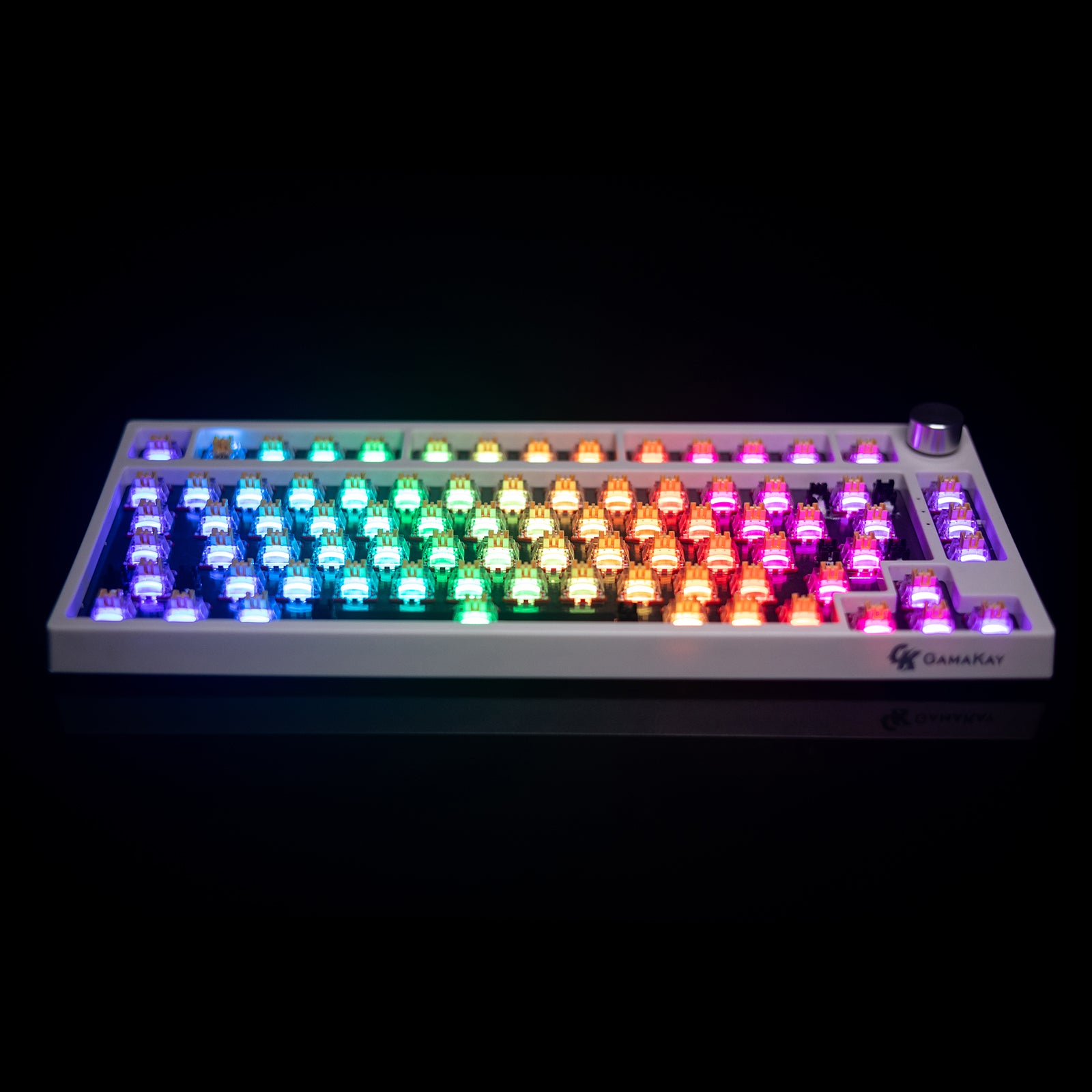 Close-up of a GamaKay keyboard featuring Silent Switch V2s with translucent housings. The switches glow with a vivid RGB gradient effect, diffusing colorful light smoothly from blue and green on the left to orange and pink on the right, with no keycaps installed.