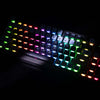 A close-up view of a Gamakay LK75 mechanical keyboard with a black base and vibrant, rainbow-colored backlighting. The keys are illuminated from beneath, creating a colorful spectrum that stands out against the dark background. The focus is on the individ