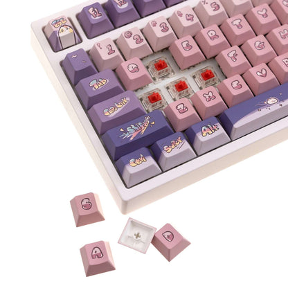 Purple and pink keycaps with space cat illustrations on a compact mechanical keyboard